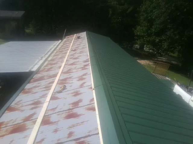 Old rusted panels beside newly installed green metal roofing — Wind Damage Roof Repair by Roofing Brothers in Fort Myer