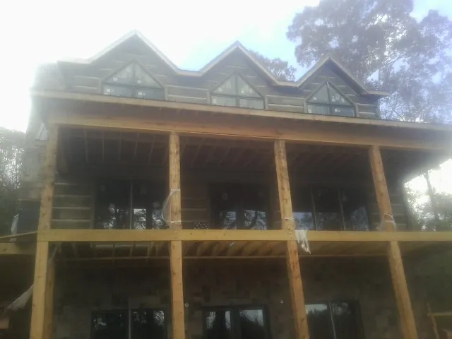 Dormers and porch framing on a large log home under construction — Roof Coating work by our crew in Fort Myer