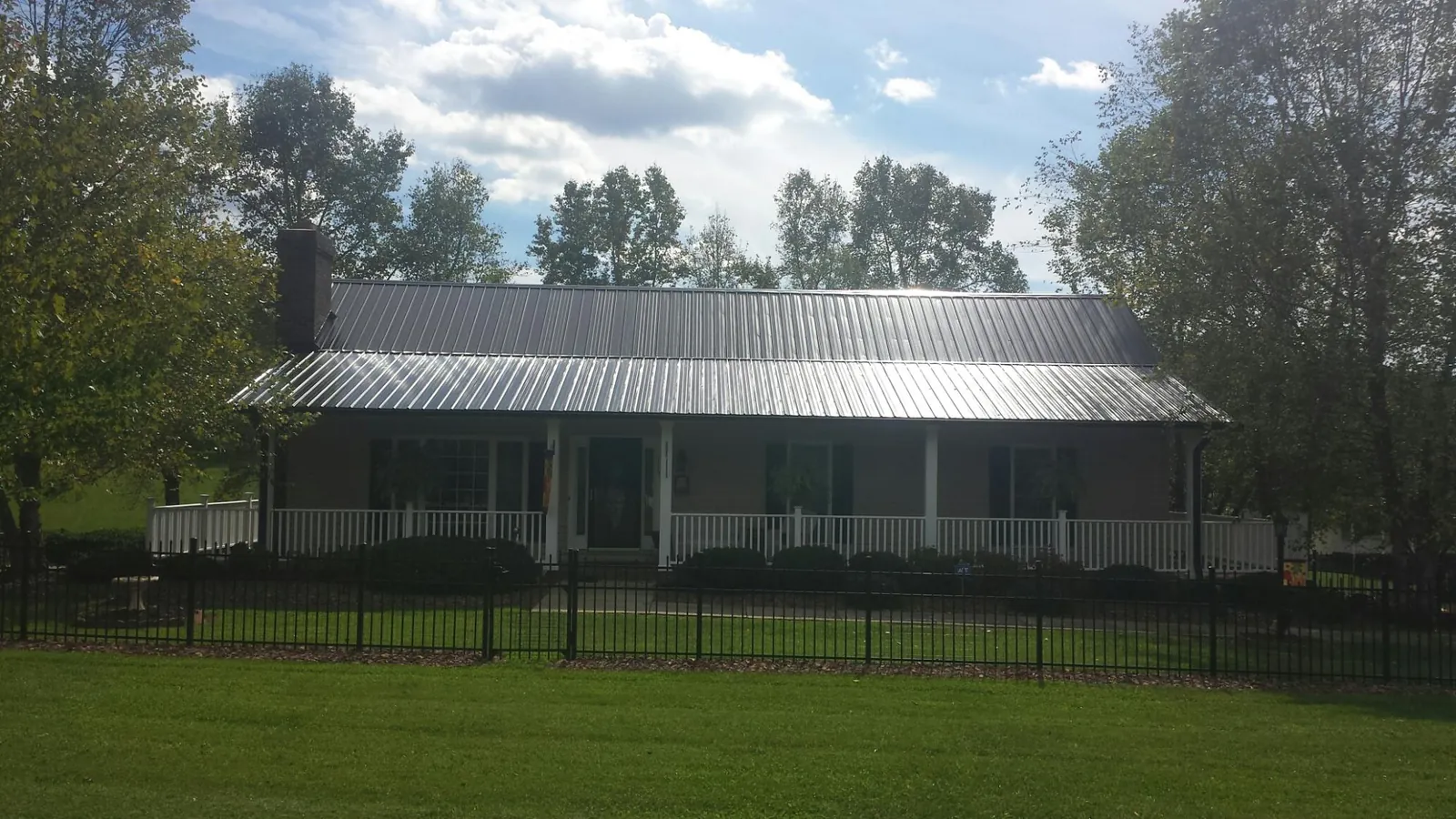Gray metal roof on a brick ranch with a full width front porch — Gutter Guard Installation work by our crew in Fort Myer