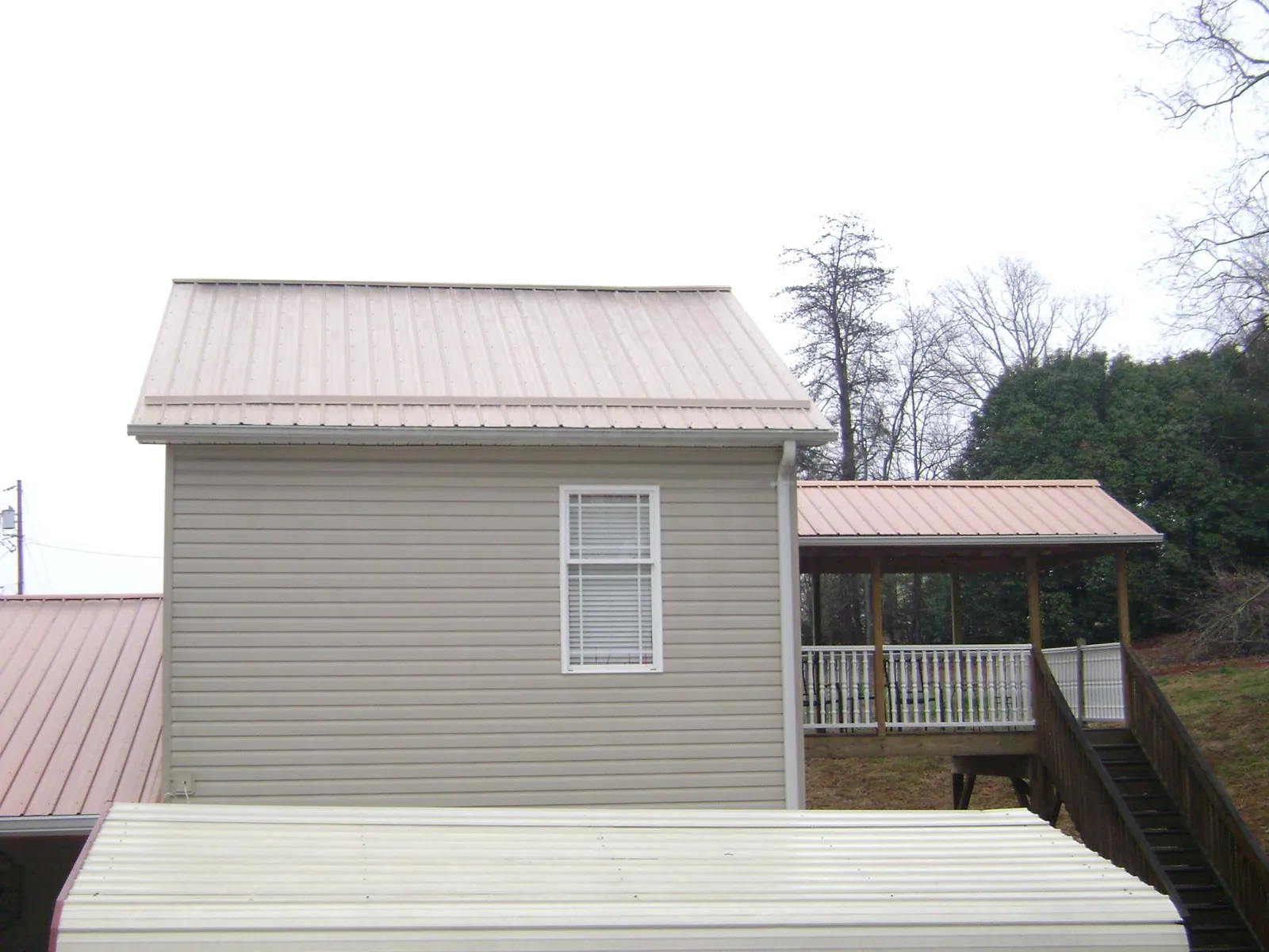 Tan metal roofs on a two story addition and attached porch, from a Roof Replacement job in Fort Myer
