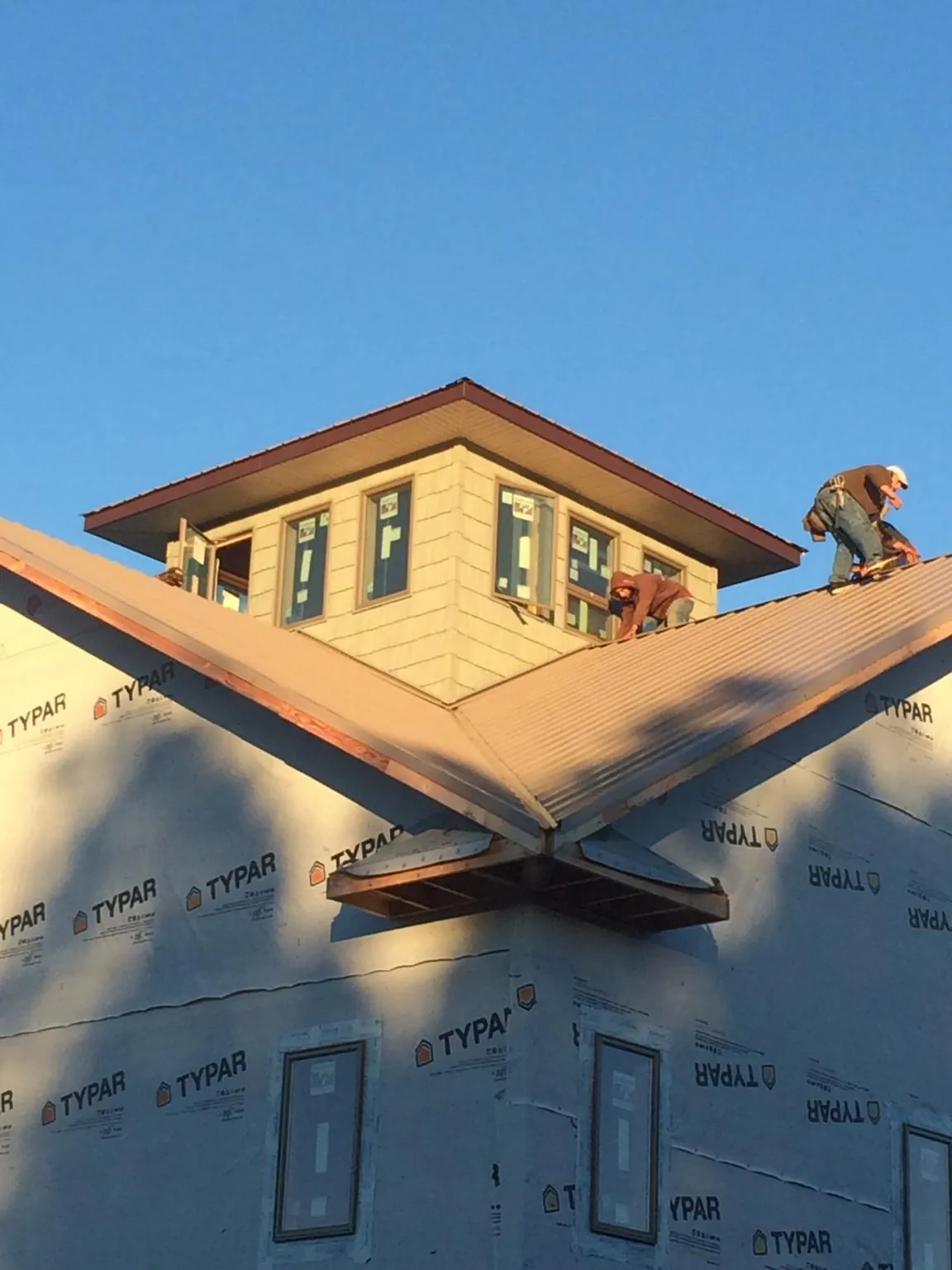 Roofers working around a rooftop cupola on a new metal roof at sunset — Roof Waterproofing in Fort Myer by Roofing Brothers